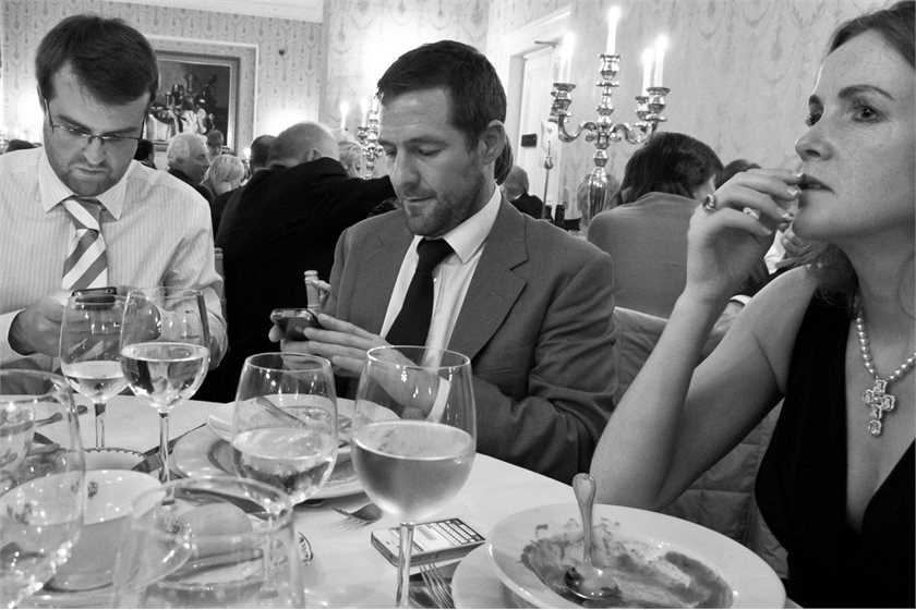 Young couple conversing on phone rather than to their children when in restaurant